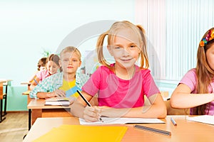 Kids sitting at table in classroom and writing