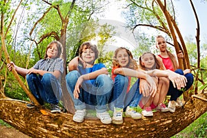 Kids sitting on trunk of fallen tree in the forest