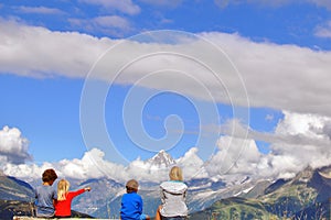 Kids sitting at viewpoint in mountains