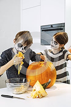 Kids with skull face paint carving a pumpkin