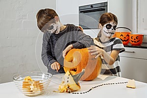 Kids with skull facepaint cutting a pumpkin