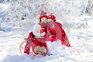 Kids sledding in winter forest. Children drink hot cocoa in snow