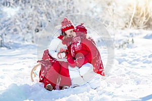 Kids sledding in winter forest. Children drink hot cocoa in snow