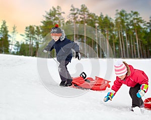 kids with sleds climbing snow hill in winter