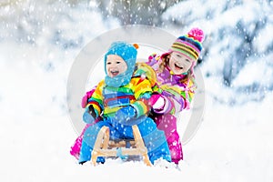 Kids on sleigh ride. Children sledding. Winter snow fun.