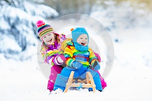 Kids on sleigh ride. Children sledding. Winter snow fun.