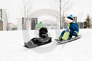 Kids sliding on sleds down snow hill in winter