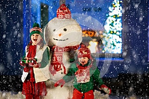 Kids and snowman in garden at Christmas fireplace