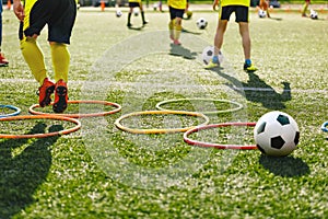 Kids soccer players moving speed tests and jogging and jumping between hula hoops for football training