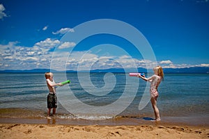 Kids squirting each other with water at the beach photo