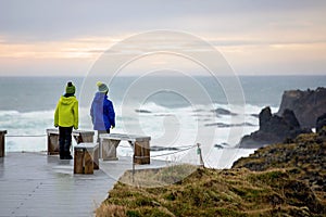 Kids standing on shore of the ocean, beautiful nature in Snaefellsjokull National Park in Iceland, autumntime