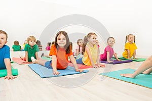 Kids stretching backs on yoga mats in sports club photo