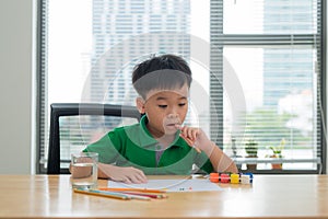 Kids at study table thinking.Kid holding a pen and a notebook wi