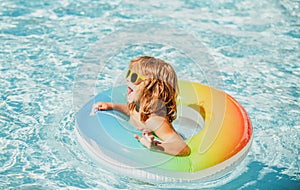 Kids summer vacation. Child swimming in pool. Kid having fun at aquapark. Funny boy on inflatable rubber circle