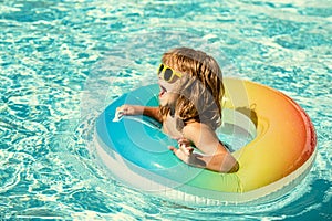 Kids summer vacation. Child swimming in pool. Kid having fun at aquapark. Funny boy on inflatable rubber circle