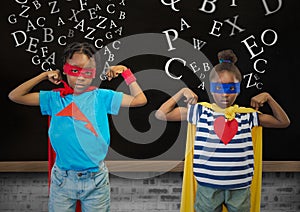 Kids in superhero costume flexing their arms against blackboard in background