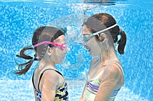 Kids swim in swimming pool underwater, little active girls have fun under water, children fitness and sport