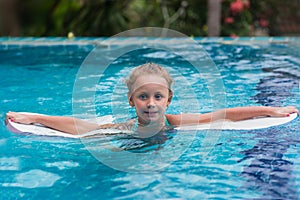 Kids in swimming pool. Children swim outdoors. Toddler child during vacation in a tropical resort with palm trees.