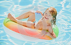 Kids Swimming with Swim Ring. Happy kid playing with colorful swim ring in swimming pool on summer day. Child water toys