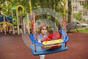 Kids swing. Emotional girl playing interactively on the playground.