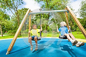 Kids on swings staring at each other and sit