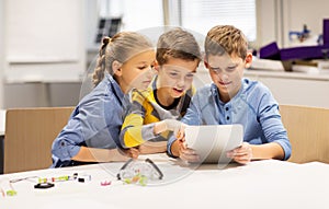 Kids with tablet pc programming at robotics school