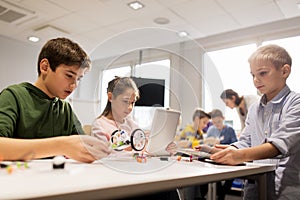 Kids with tablet pc programming at robotics school