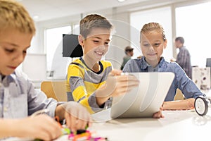 Kids with tablet pc programming at robotics school