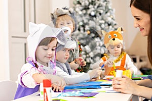 Kids with teacher make hands crafts in kindergarten. Children prepare to christmas. Group orf preschoolers on lesson in