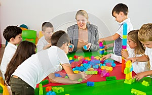 Kids with teacher playing with building blocks