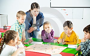 Kids with teacher playing educational tabletop game