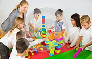 Kids and teacher playing with toy building blocks