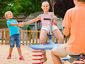 kids are teetering on the swing on the playground.