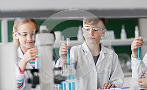 Kids with test tubes studying chemistry at school