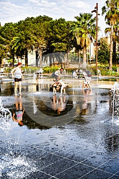 Kids and their parents play in the water fountain