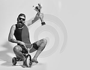 Kids toys. bearded happy man holds gold champion cup on bicycle toy