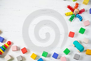 Kids toys frame wooden blocks, octopus, car, pyramidion on white wooden background. Top view. Flat lay. Copy space for text.