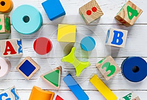 Kids toys: pyramid, wooden blocks, frame on white wooden background. Education, games for preschool. Top view. Flat lay