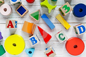 Kids toys: pyramid, wooden blocks,  train frame on white wooden background. Education, games for preschool. Top view.