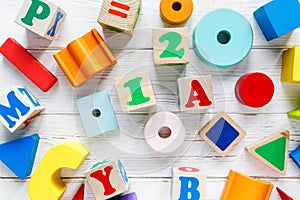 Kids toys: pyramid, wooden blocks, train frame on white wooden background. Education, games for preschool. Top view.