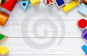 Kids toys: pyramid, wooden blocks, train frame on white wooden background. Education, games for preschool. Top view. Flat lay.