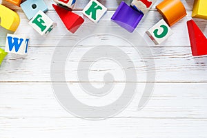 Kids toys: pyramid, wooden blocks,  train frame on white wooden background. Education, games for preschool. Top view. Flat lay.