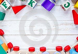 Kids toys: pyramid, wooden blocks, train frame on white wooden background. Education, games for preschool. Top view. Flat lay.