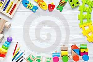 Kids toys: pyramid, wooden blocks, xylophone, train on white wooden background.