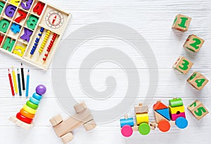 Kids toys: pyramid, wooden blocks, xylophone, train on white wooden background.