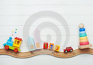 Kids toys on toy wooden railway on white wooden background