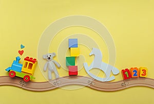 Kids toys on toy wooden railway on yellow background