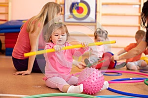 Kids and trainer playing with sport equipment in kindergarten gym