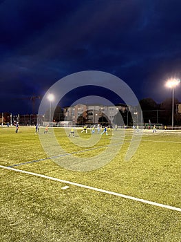 Kids training football under floodlights in Toulouse city.