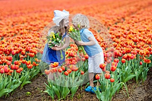 Kids in tulip flower field. Windmill in Holland